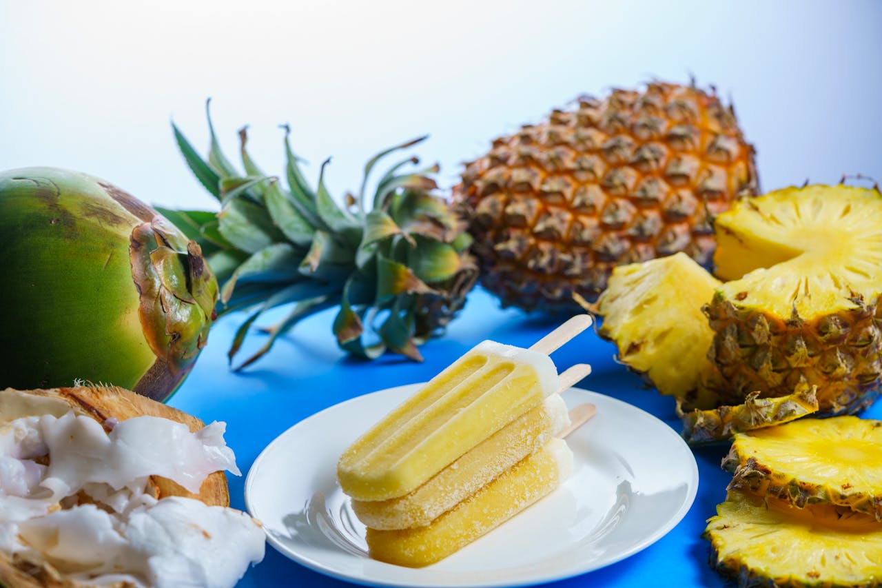 Refreshing tropical fruit popsicles with pineapples and coconuts on a plate, ideal for summer treats.