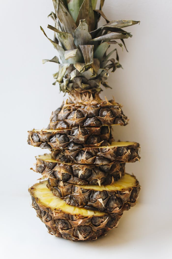 A close-up view of a ripe, sliced pineapple artistically stacked against a clean white backdrop.